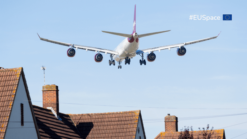 Ein Flugzeug überfliegt Wohnhäuser. In der oberen rechten Ecke des Bildes befindet sich der Schriftzug #EUSpace neben einer Europa-Flagge. Ein Flugzeug überfliegt Wohnhäuser. In der oberen rechten Ecke des Bildes befindet sich der Schriftzug #EUSpace neben einer Europa-Flagge.