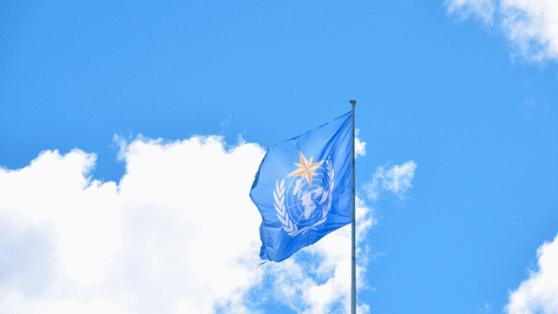 Flagge der WMO vor blauem Himmel mit Wolken Flagge der WMO vor blauem Himmel mit Wolken