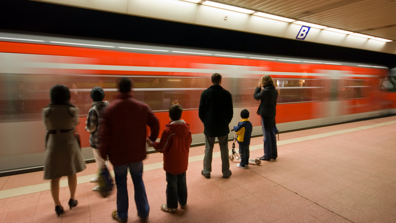 Einfahrender Zug und wartende Menschen am Bahnsteig Einfahrender Zug und wartende Menschen am Bahnsteig