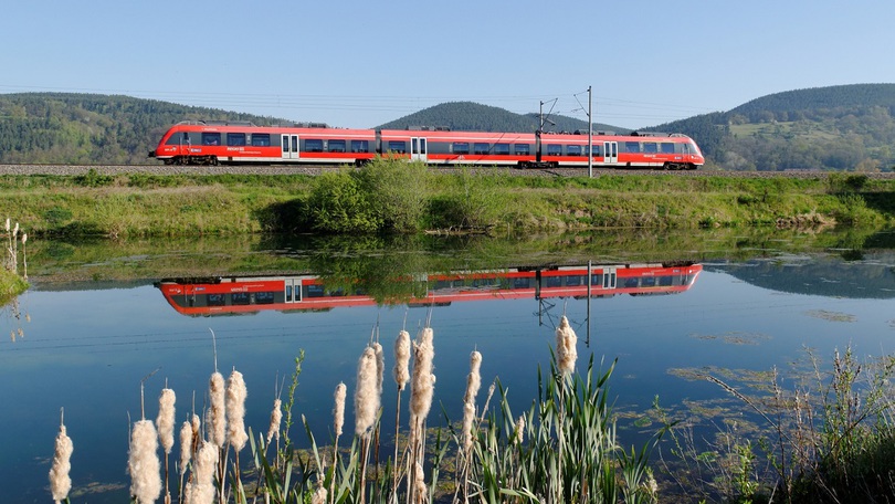 Eine Regionalbahn fährt durch eine hügelige Landschaft Eine Regionalbahn fährt durch eine hügelige Landschaft